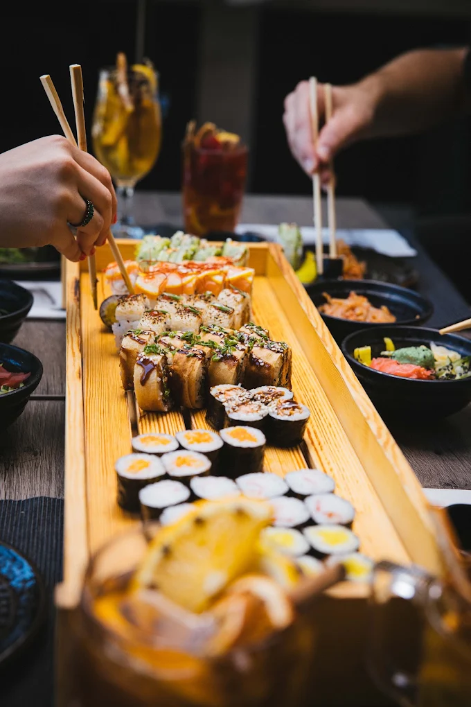 Goście restauracji Koku Sushi sięgający po sushi podane na drewnianej tacy